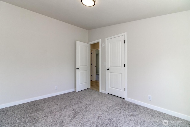carpeted spare room featuring baseboards