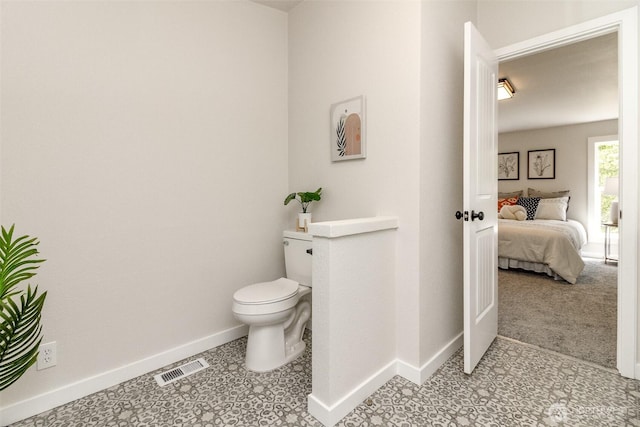 bathroom with baseboards, toilet, and connected bathroom