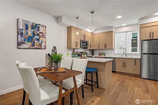 105B NW 39th St, Seattle, WA 98107 - kitchen featuring appliances with stainless steel finishes, a sink, light countertops, light wood-style flooring, and a kitchen breakfast bar