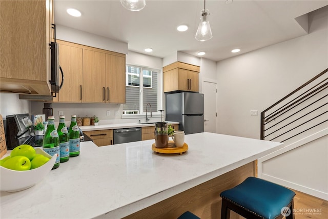 105B NW 39th St, Seattle, WA 98107 - kitchen featuring stainless steel appliances, a peninsula, a breakfast bar, decorative light fixtures, and a sink