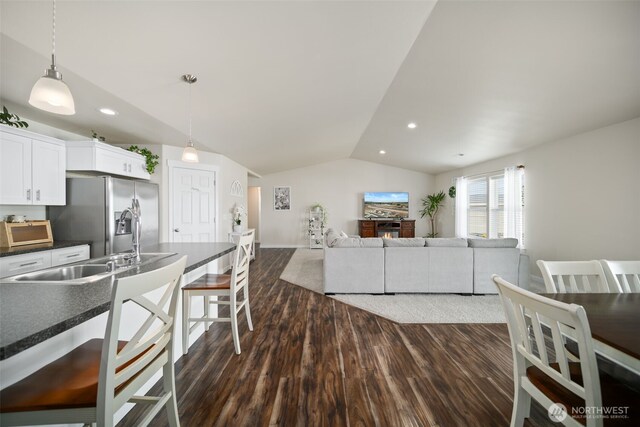 1620 2nd Ave SW, Quincy, WA 98848 - kitchen with stainless steel refrigerator with ice dispenser, dark countertops, lofted ceiling, a breakfast bar area, and dark wood-style flooring