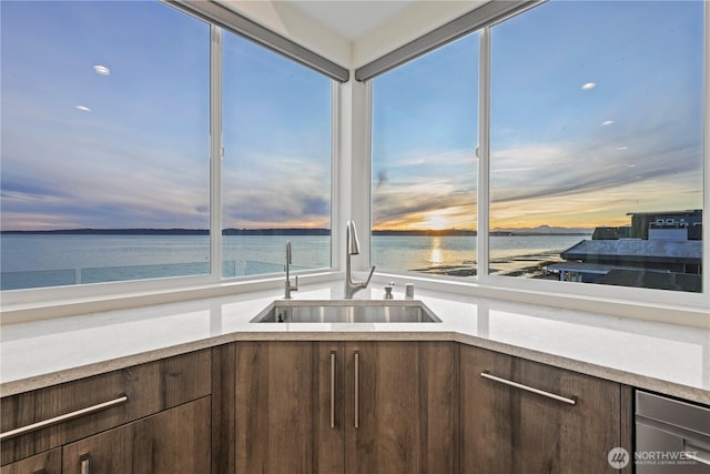 12065 30th Ave SW, Burien, WA 98146 - kitchen with dark brown cabinetry, a sink, light countertops, and a water view