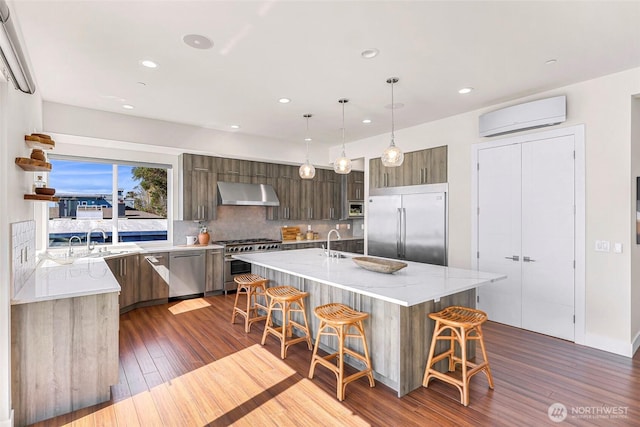 12065 30th Ave SW, Burien, WA 98146 - kitchen featuring high quality appliances, wall chimney exhaust hood, a wall mounted AC, modern cabinets, and a breakfast bar