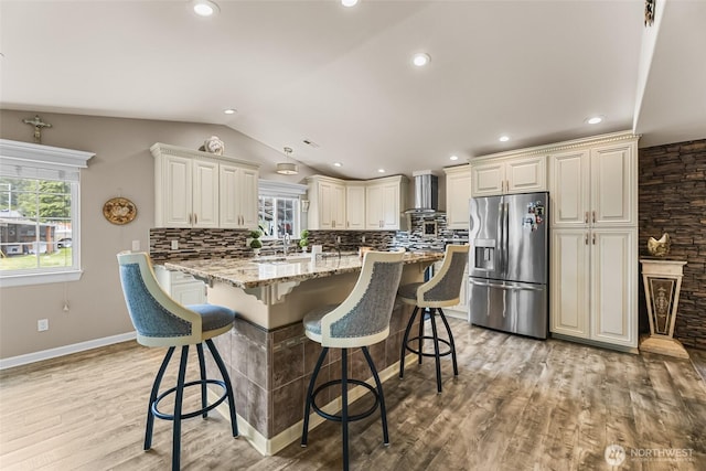 3001 163rd St E, Tacoma, WA 98446 - kitchen with stainless steel fridge with ice dispenser, wall chimney range hood, plenty of natural light, lofted ceiling, and light wood finished floors