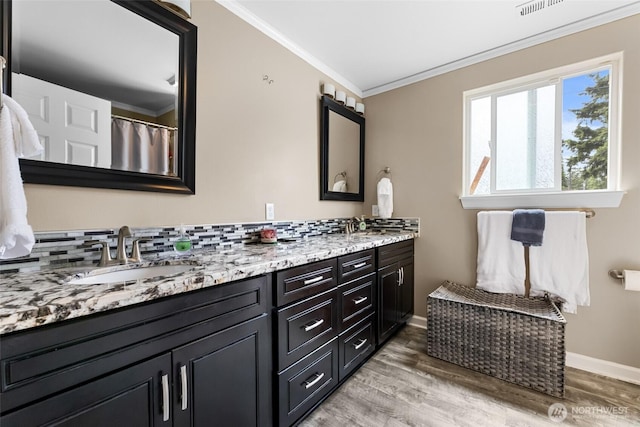 3001 163rd St E, Tacoma, WA 98446 - bathroom featuring ornamental molding, double vanity, decorative backsplash, wood finished floors, and baseboards
