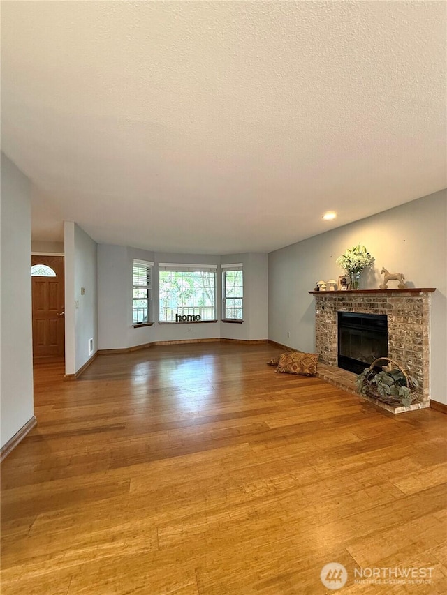 21849 SE 266th Pl, Maple Valley, WA 98038 - unfurnished living room featuring wood finished floors, a fireplace, baseboards, and recessed lighting