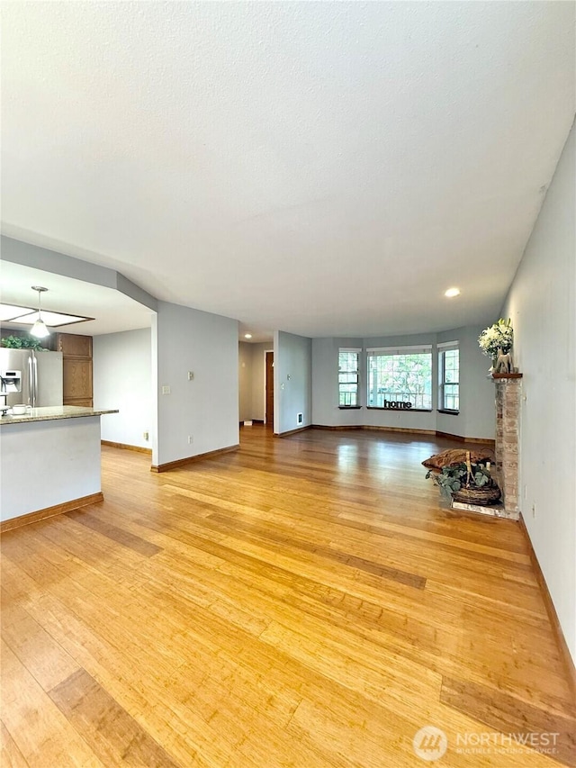 21849 SE 266th Pl, Maple Valley, WA 98038 - unfurnished living room featuring light wood finished floors, baseboards, and a fireplace