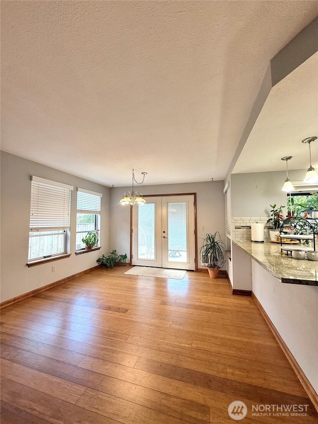 21849 SE 266th Pl, Maple Valley, WA 98038 - unfurnished living room with light wood-style flooring, baseboards, a textured ceiling, french doors, and a chandelier