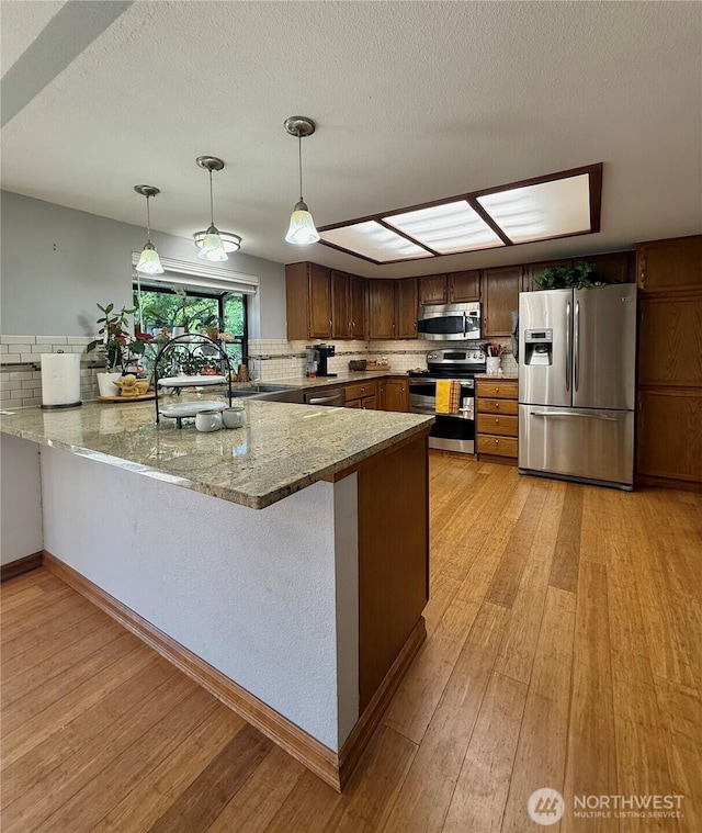 21849 SE 266th Pl, Maple Valley, WA 98038 - kitchen with stainless steel appliances, a sink, light wood-style flooring, a peninsula, and light stone counters