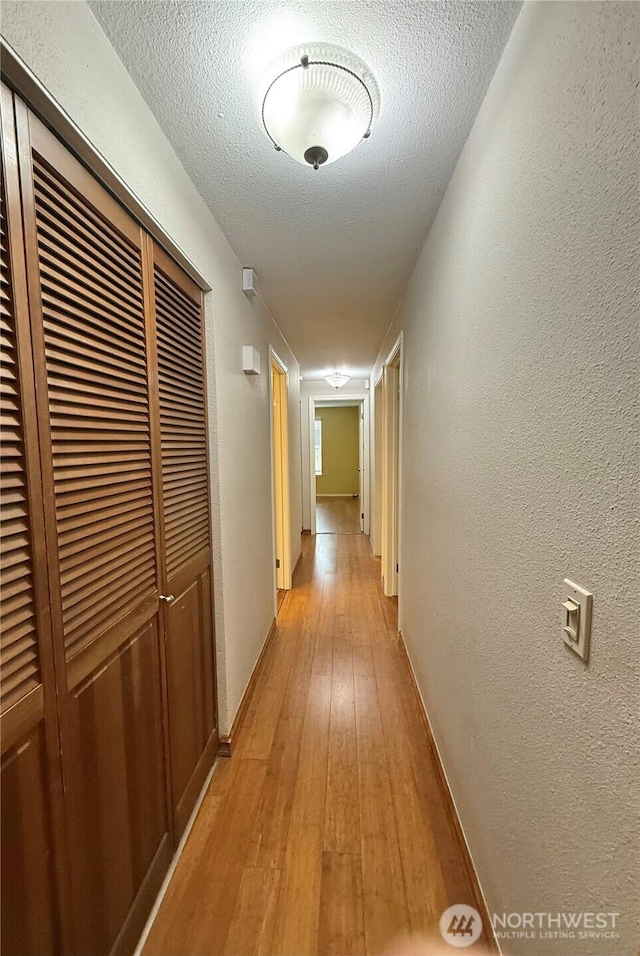 21849 SE 266th Pl, Maple Valley, WA 98038 - hallway featuring light wood-style flooring, a textured wall, a textured ceiling, and baseboards