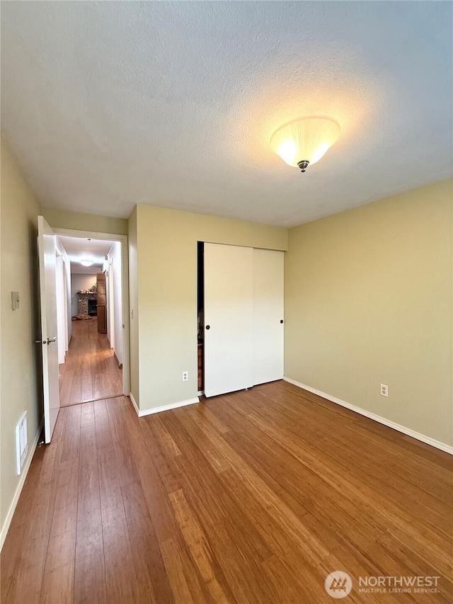 21849 SE 266th Pl, Maple Valley, WA 98038 - unfurnished bedroom with wood-type flooring, baseboards, a closet, and a textured ceiling