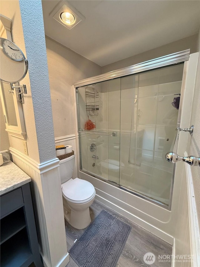 21849 SE 266th Pl, Maple Valley, WA 98038 - bathroom featuring toilet, bath / shower combo with glass door, vanity, wood finished floors, and wainscoting