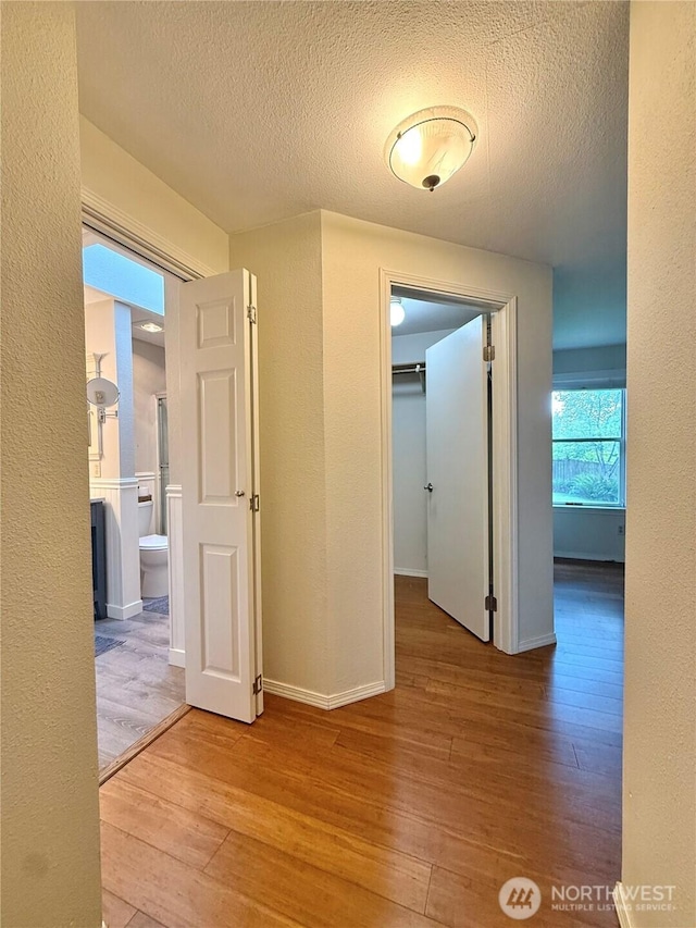 21849 SE 266th Pl, Maple Valley, WA 98038 - corridor with hardwood / wood-style floors, a textured ceiling, a textured wall, and baseboards