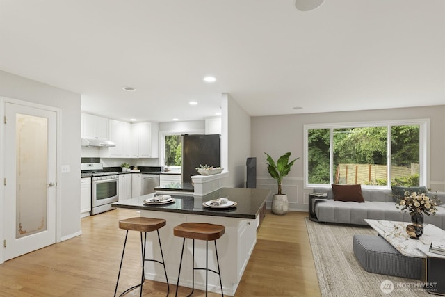 820 173rd Ave NE, Bellevue, WA 98008 - kitchen featuring appliances with stainless steel finishes, under cabinet range hood, dark countertops, white cabinetry, and healthy amount of natural light