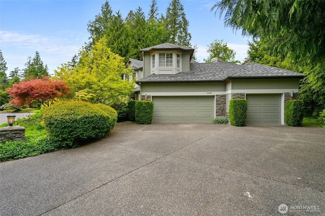 5426 Quail Run, Blaine, WA 98230 - view of front of property featuring driveway, stone siding, an attached garage, and a chimney