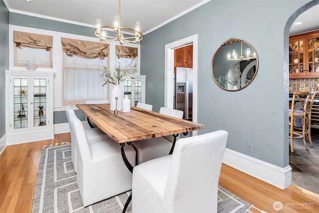 903 W Newell St, Seattle, WA 98119 - dining room with a chandelier, light wood finished floors, ornamental molding, arched walkways, and baseboards