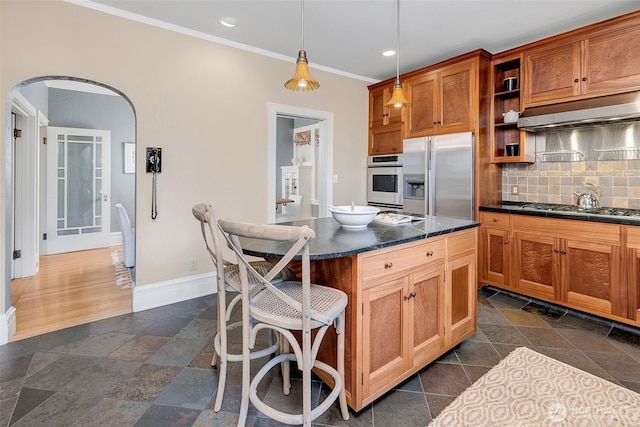 903 W Newell St, Seattle, WA 98119 - kitchen with stainless steel appliances, dark countertops, under cabinet range hood, baseboards, and a kitchen bar