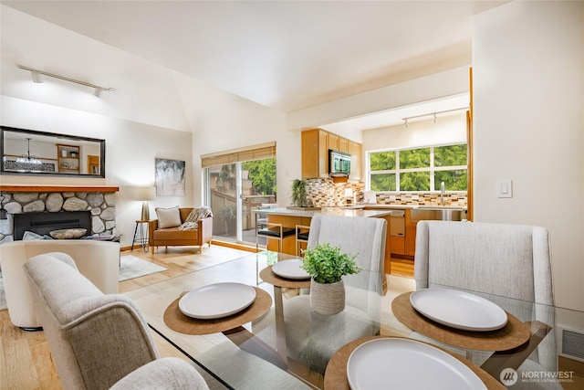 5430 Snow Goose Ln Unit 202, Blaine, WA 98230 - dining space featuring track lighting, light wood-style floors, a stone fireplace, and lofted ceiling