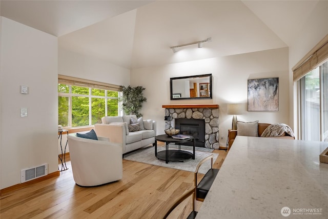 5430 Snow Goose Ln Unit 202, Blaine, WA 98230 - living room featuring light wood-style flooring, rail lighting, a stone fireplace, and high vaulted ceiling