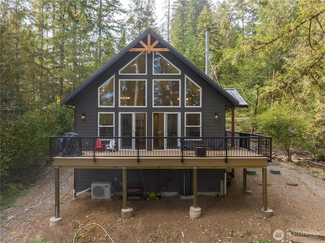 rear view of house featuring a wooden deck, a cooling unit, a view of trees, and central AC unit