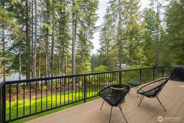 wooden deck with a water view, area for grilling, and a yard