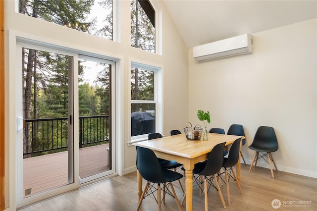 dining room featuring a wall mounted air conditioner, wood finished floors, high vaulted ceiling, and baseboards