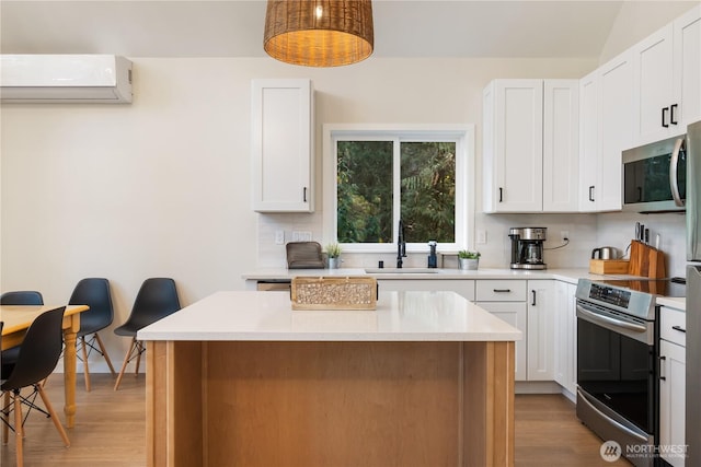 kitchen featuring appliances with stainless steel finishes, an AC wall unit, decorative backsplash, and light wood-style floors