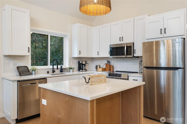 kitchen featuring appliances with stainless steel finishes, a sink, backsplash, light countertops, and white cabinetry