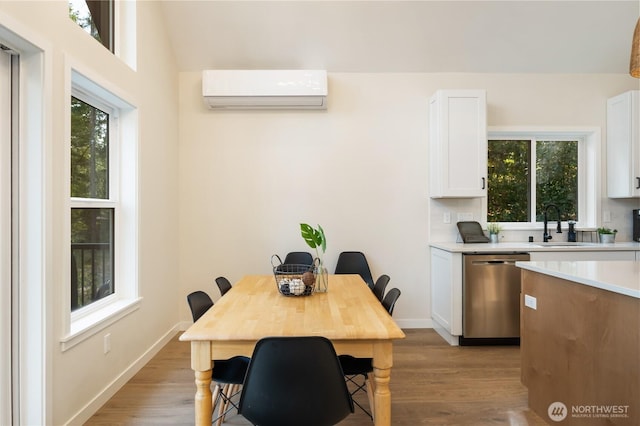 dining space with an AC wall unit, light wood-style floors, and baseboards