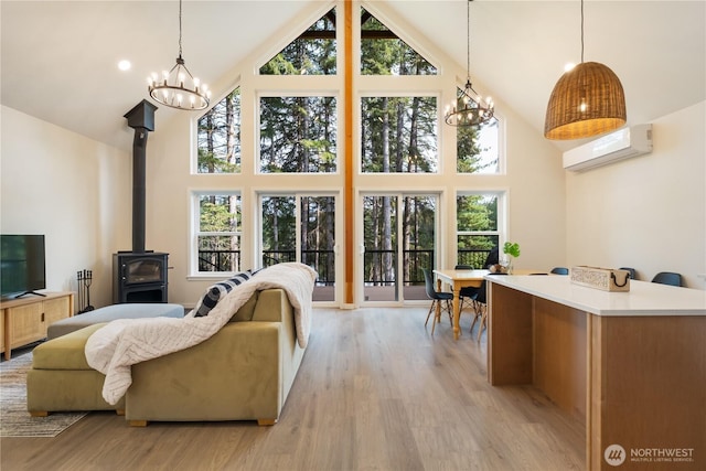 living area with high vaulted ceiling, a chandelier, a wall unit AC, and light wood finished floors