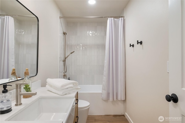 full bath featuring wood finished floors, shower / bath combination with curtain, toilet, and vanity
