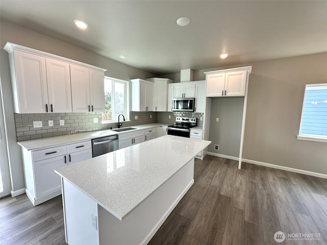 447 S Spinnaker St SW, Ocean Shores, WA 98569 - kitchen featuring stainless steel appliances, a sink, dark wood-style floors, white cabinets, and backsplash