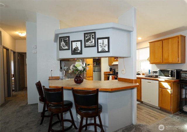 1427 100th St SW Unit 57, Everett, WA 98204 - kitchen featuring white dishwasher, stainless steel microwave, a breakfast bar, light countertops, and a peninsula