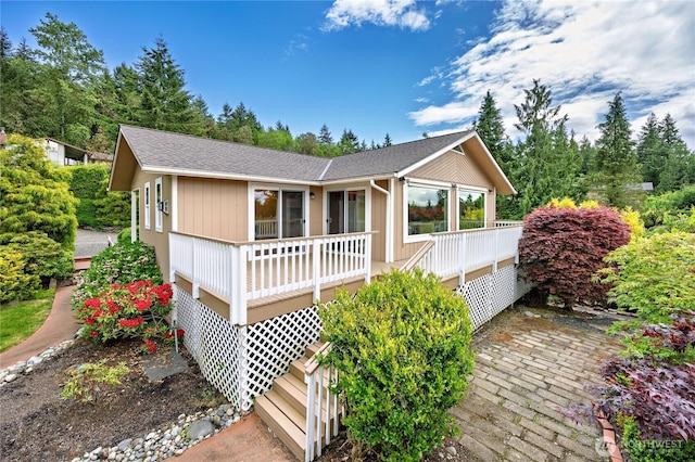ranch-style house featuring a wooden deck and a shingled roof