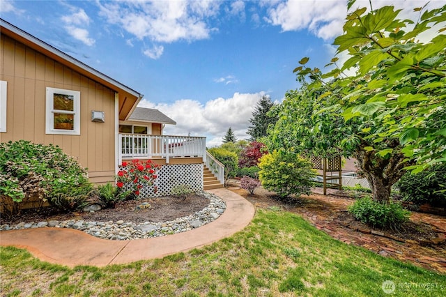 view of grassy yard featuring stairway and a wooden deck