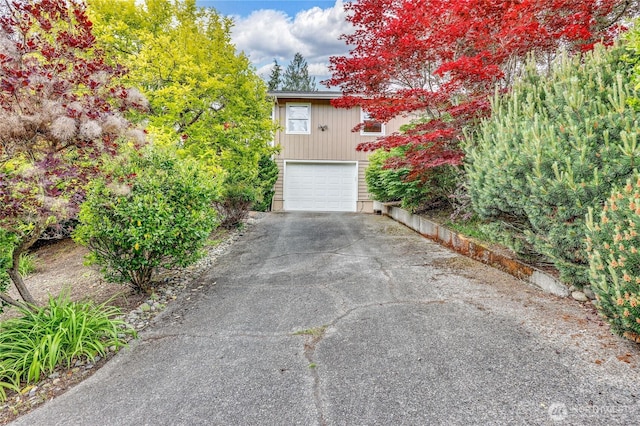 view of property hidden behind natural elements with driveway and an attached garage