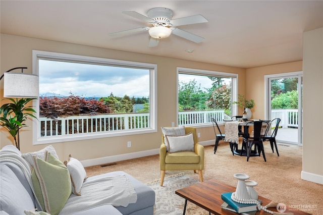 carpeted living room featuring baseboards and a ceiling fan