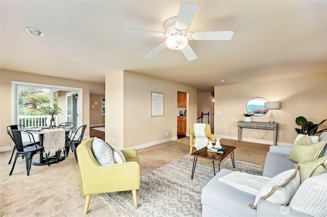 living area with light colored carpet, baseboards, and ceiling fan