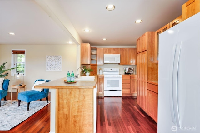 kitchen featuring white appliances, a sink, a peninsula, recessed lighting, and dark wood-type flooring