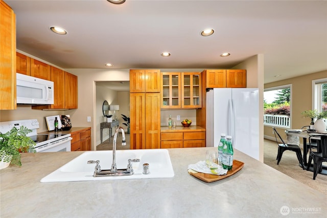 kitchen featuring white appliances, light countertops, a sink, glass insert cabinets, and recessed lighting