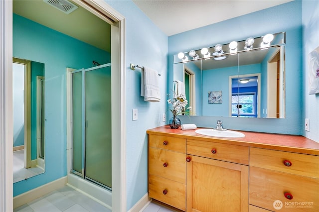 bathroom with a shower stall, vanity, baseboards, and tile patterned flooring