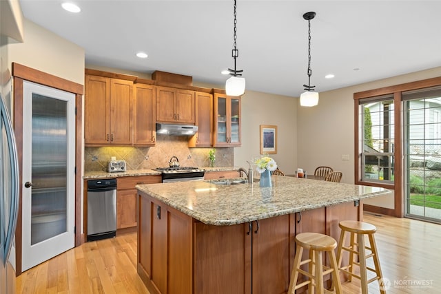 1051 N Baker Unit B104, East Wenatchee, WA 98802 - kitchen with under cabinet range hood, stainless steel range with gas cooktop, light wood finished floors, a sink, and brown cabinets