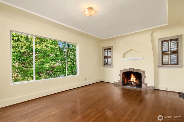 unfurnished living room with a brick fireplace, wood finished floors, and baseboards