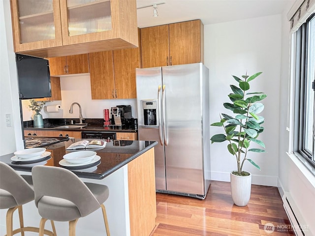 1105 Spring St Unit 904, Seattle, WA 98104 - kitchen featuring stainless steel refrigerator with ice dispenser, a sink, a baseboard heating unit, dark countertops, and light wood-type flooring