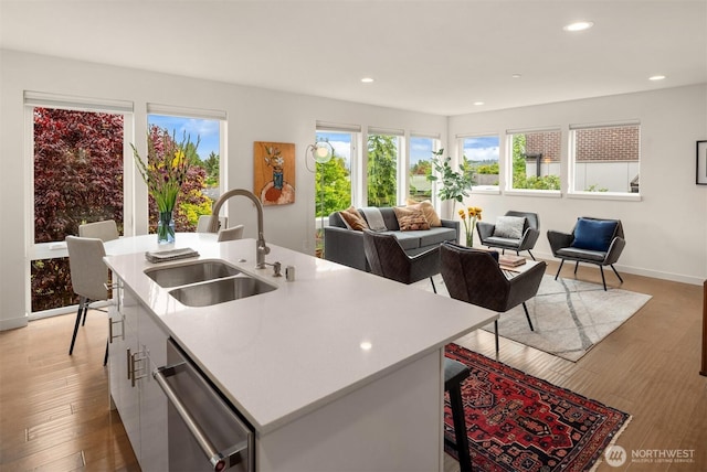 4321 S Webster St # E, Seattle, WA 98118 - kitchen with a sink, stainless steel dishwasher, light countertops, a center island with sink, and light wood-type flooring