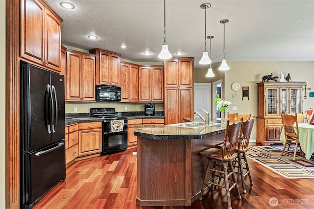 108 Reynolds Rd, Castle Rock, WA 98611 - kitchen with black appliances, a sink, wood finished floors, a breakfast bar, and recessed lighting