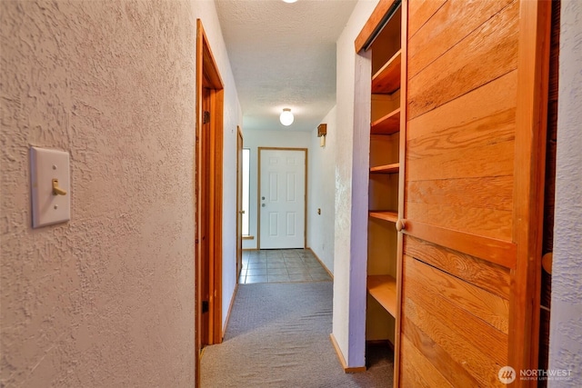 257 Point Brown Ave SW, Ocean Shores, WA 98569 - hallway featuring carpet flooring, a textured wall, tile patterned floors, baseboards, and a textured ceiling