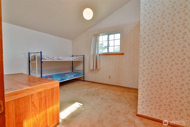 257 Point Brown Ave SW, Ocean Shores, WA 98569 - unfurnished bedroom featuring lofted ceiling, carpet, baseboards, and wallpapered walls