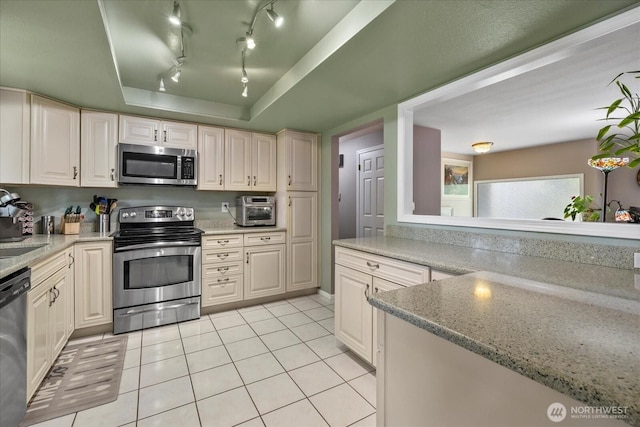 17631 69th Pl W, Edmonds, WA 98026 - kitchen with stainless steel appliances, light tile patterned flooring, light stone countertops, and a tray ceiling