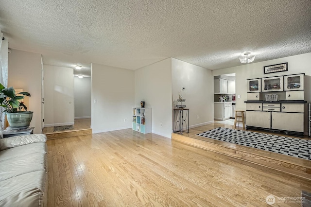 8918 108th St SW, Lakewood, WA 98498 - unfurnished living room featuring light wood-style floors, a textured ceiling, and baseboards